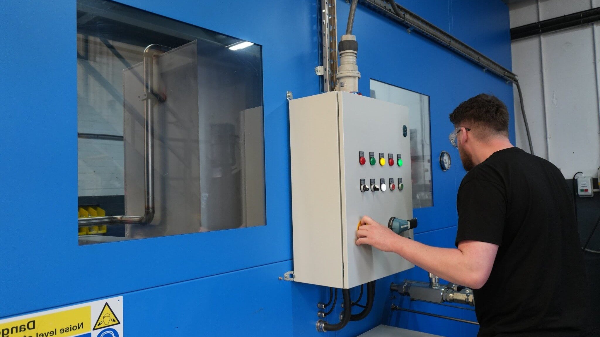 Person operating a machine with control panel in a workshop setting